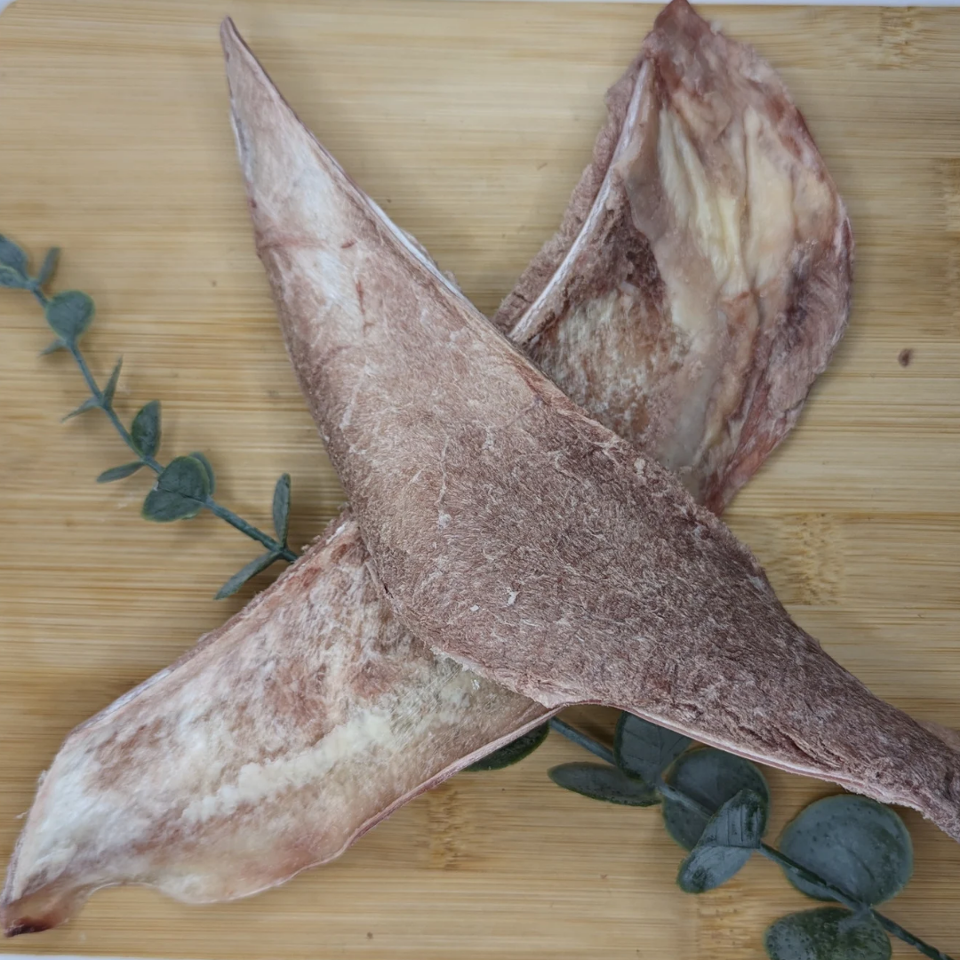 Two pieces of Beast Feast freeze-dried bison scapula slices on a cutting board.