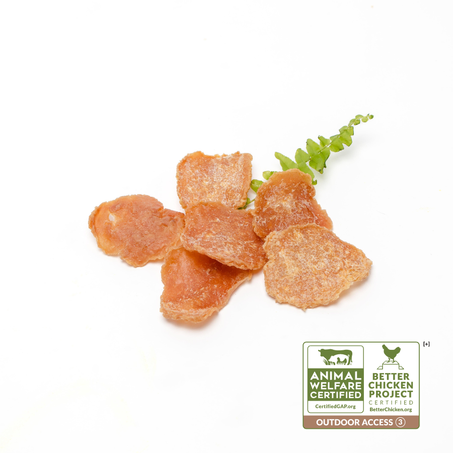 Several dried meat slices are arranged with a small green leafy garnish. The image includes labels for "Animal Welfare Certified" and "Better Chicken Commitment Certified." Product Name: Chicken Crispers 1 oz, Brand Name: Wild Nosh Pets.