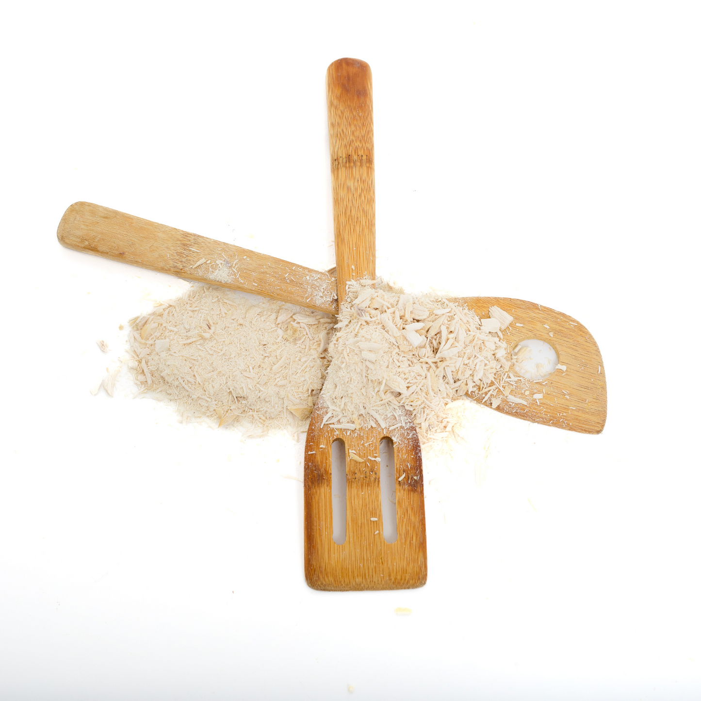 Two wooden kitchen utensils arranged in an X shape with a pile of Wild Nosh Pets Freeze-Dried Chicken Pawmesan Topper (1oz) scattered on top, perfect for picky eaters, against a white background.