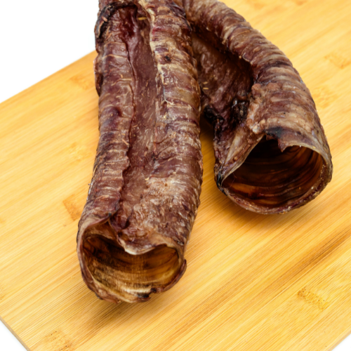 Two Dehydrated Bison Whole Trachea chews by Wild Nosh Pets rest on a wooden cutting board—ideal glucosamine treats for your furry friend.