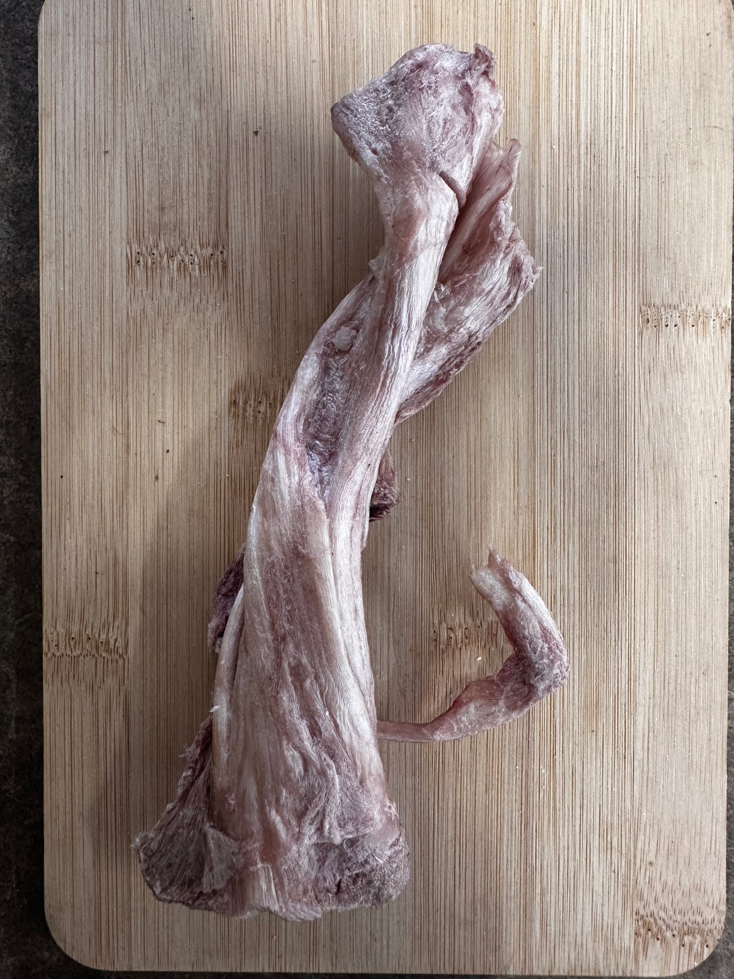 Gambrel Tendon from Wild Nosh Pets placed on a wooden cutting board.