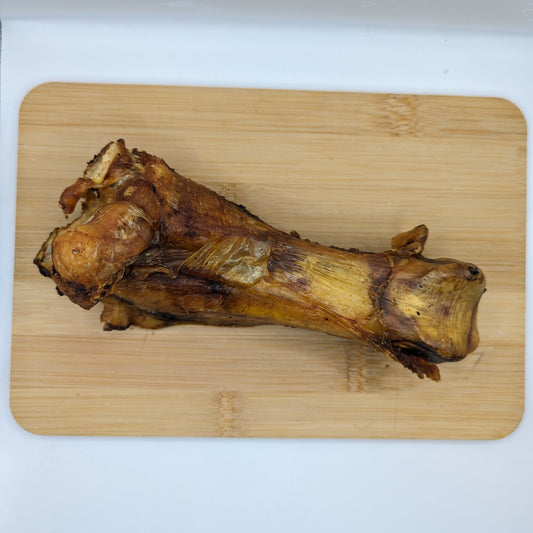 A large Wild Nosh Pets Smoked Bison Joint Bone placed on a wooden cutting board.