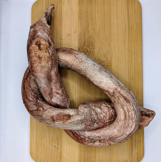 A large, curved piece of dried meat placed on a wooden cutting board, this protein-rich chew is one of our popular Wild Nosh Pets Freeze-dried Bison Bully Pretzels.