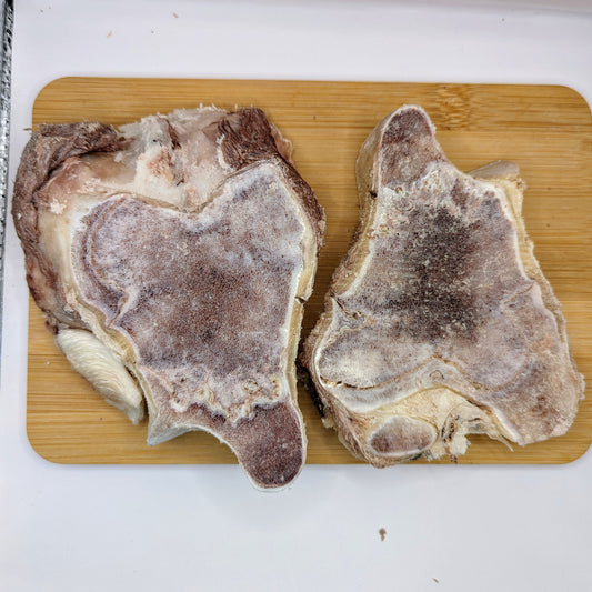 Two Freeze-Dried Bison Knuckle Slices from Wild Nosh Pets on a wooden cutting board, showcasing their robust texture and quality frost, reminiscent of premium freeze-dried raw bone treats.