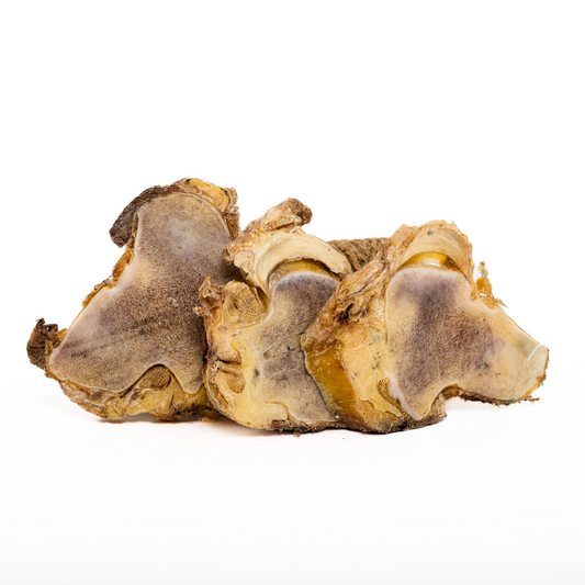 Three large Wild Nosh Pets Freeze-Dried Bison Knuckle Slices, with rough texture and brown color, are arranged side by side on a white background—ideal dog chews.