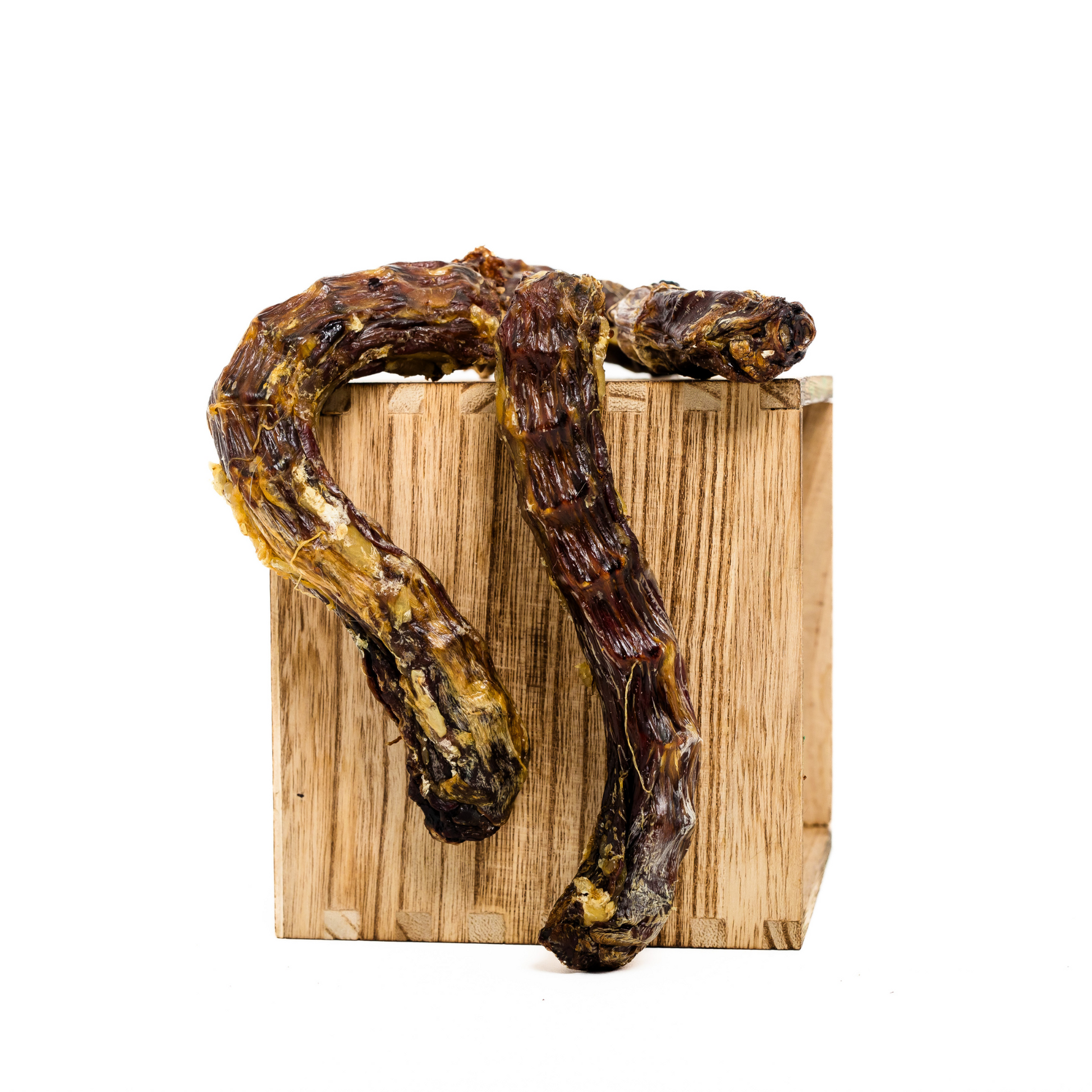 Two Dehydrated Duck Necks from Wild Nosh Pets, rich in protein, are displayed twisted on a small wooden block against a plain white background.