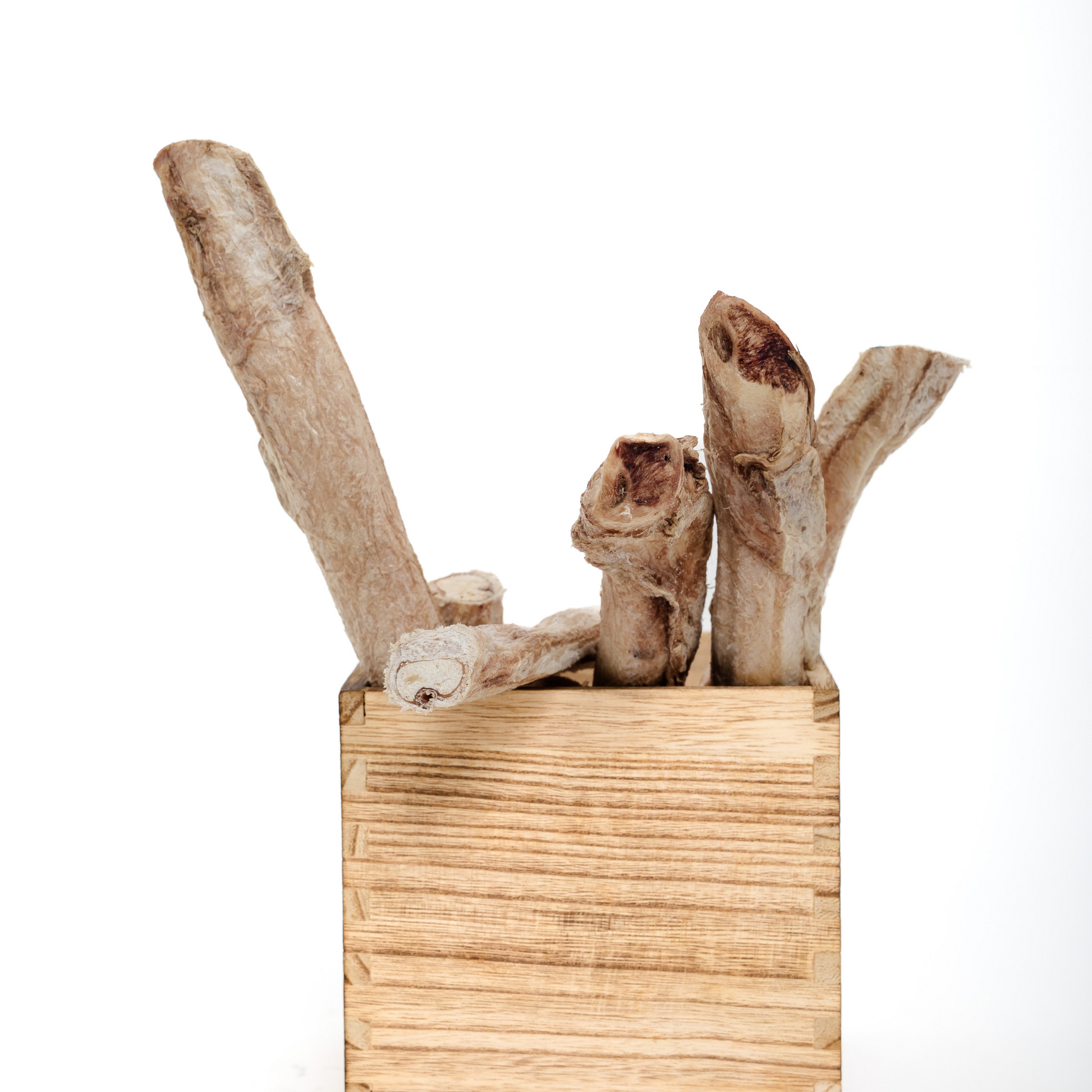 Wild Nosh Pets Freeze Dried Bison Bully Sticks stand upright in a square, light wooden container against a plain white background.