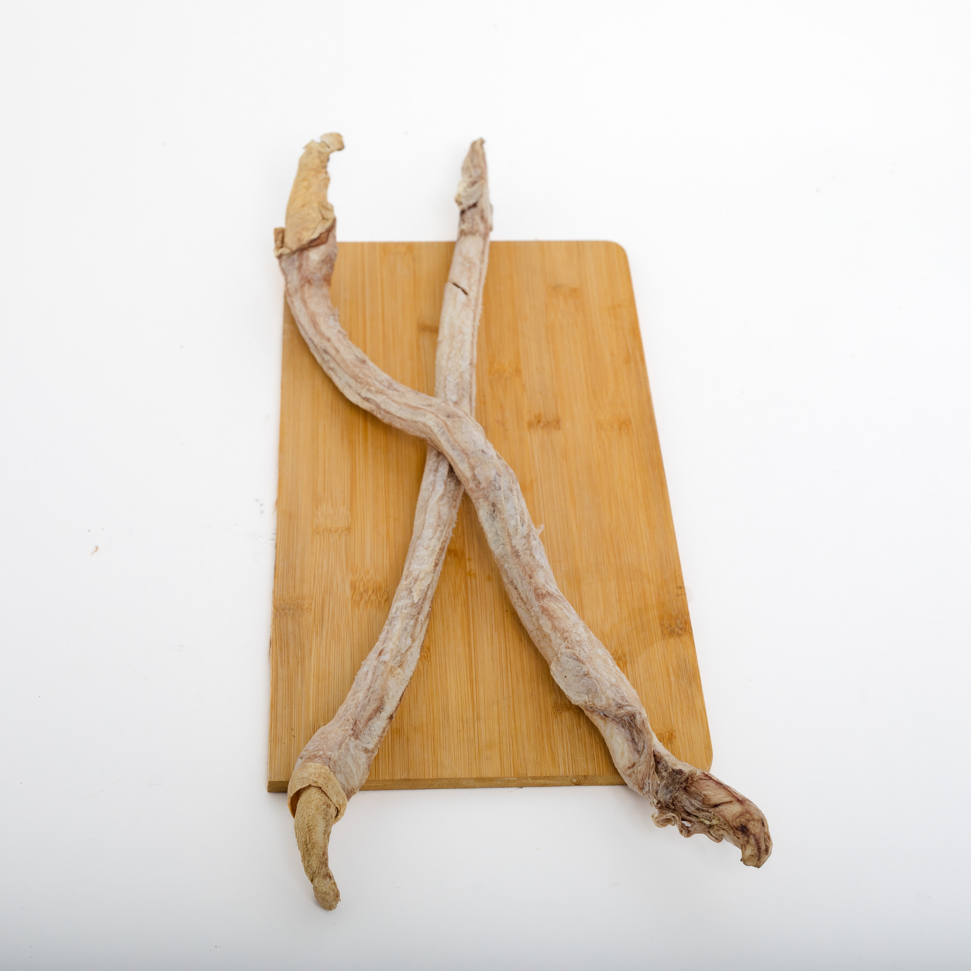 Two Freeze Dried Bison Bully Sticks from Wild Nosh Pets are crossed on a wooden cutting board against a white background, highlighting this protein-rich chew for pets.