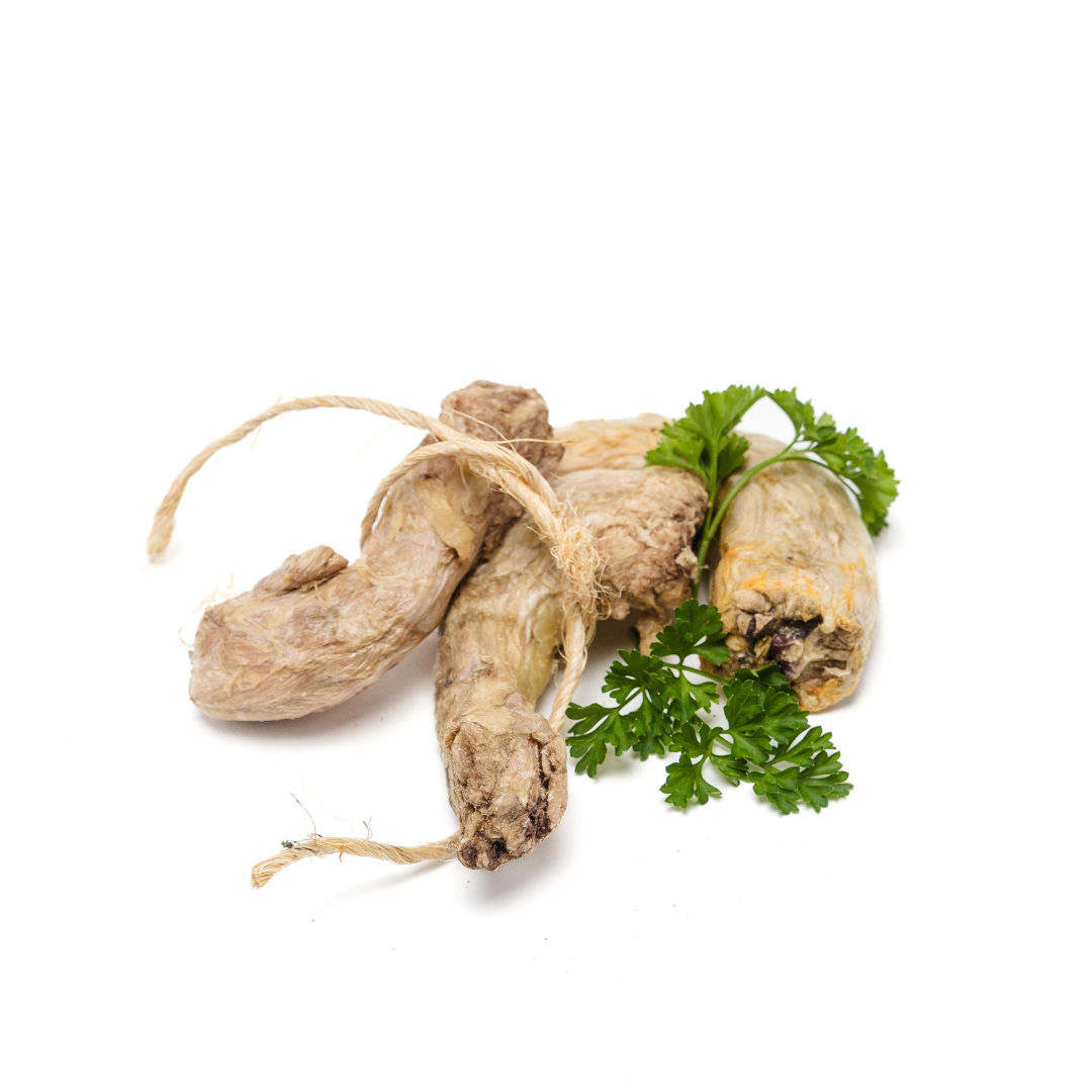 Three Freeze-Dried Chicken Necks from Wild Nosh Pets garnished with a sprig of fresh parsley on a white background, perfect for promoting joint health and clean teeth.