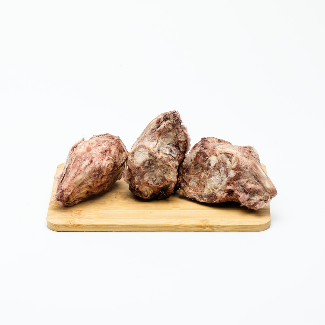 Three Wild Nosh Pets Freeze-Dried Rabbit Heads placed on a wooden cutting board against a plain white background.