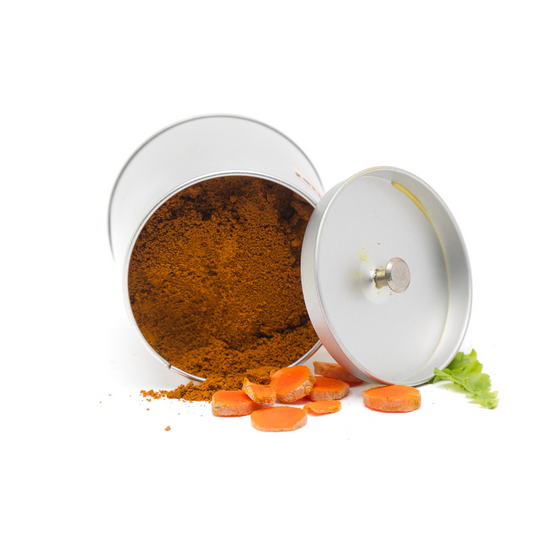 A spilled metal container of Golden Turmeric Dust by Wild Nosh Pets with orange slices and a sprig of green herb on a white background.