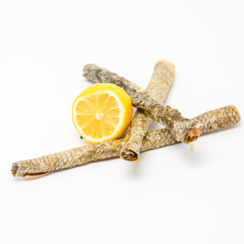 Three dried fish skins, rich in omega fatty acids, are arranged in a fan shape, with a half lemon placed on top, set against a white background. Perfect as Carp Skin Rolls by Wild Nosh Pets for dogs and cats.