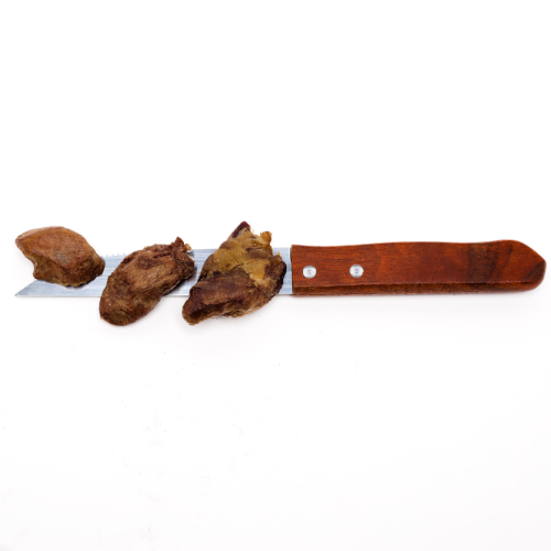 A knife with a wooden handle is placed horizontally on a white surface. Three chunks of Wild Nosh Pets Freeze-Dried Chicken Hearts 3oz, a nutritious treat for both cats and dogs, are positioned on the blade.