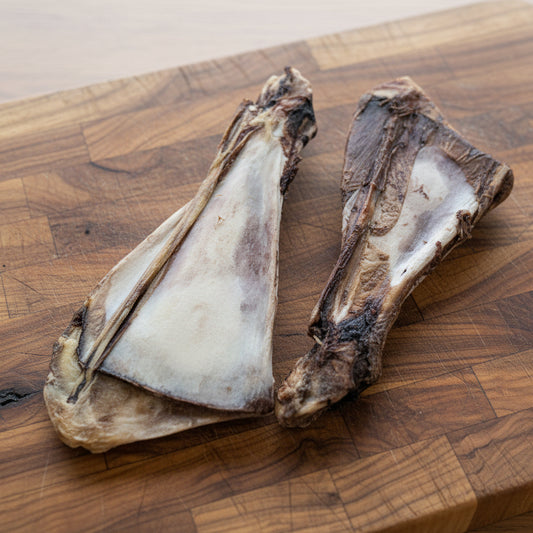 Two Wild Nosh Pets Slow Roasted Bison Paddle Bones—Limited Edition Field Harvested, 100% grass finished—rest on a wooden board: an all-natural dog chew for dental health.