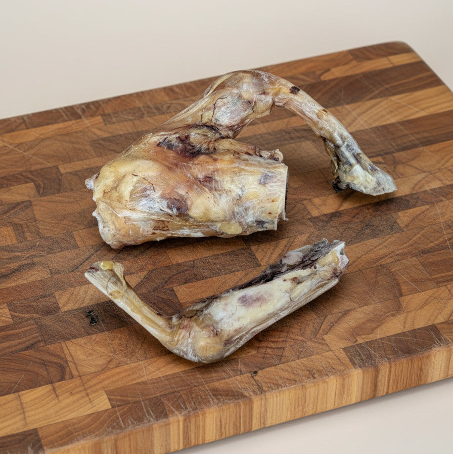 Two Slow Roasted Bison Tendon Knot treats from Wild Nosh Pets—Limited Edition, Field Harvested, 100% Grass Finished—are displayed on a wooden board, offering your pup a natural, long-lasting chew.