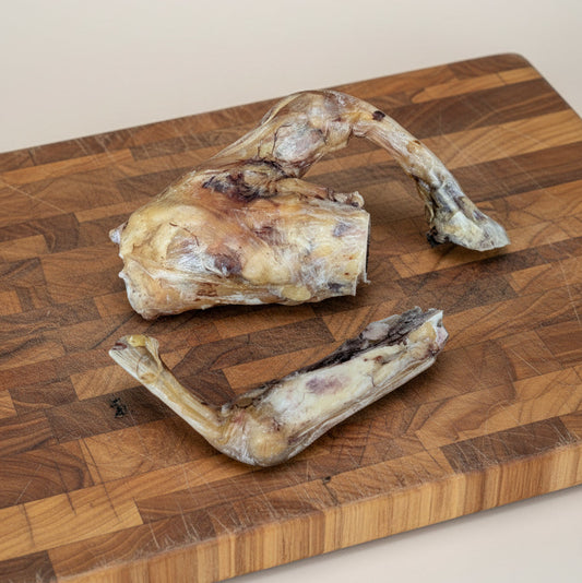 Two Slow Roasted Bison Tendon Knot treats from Wild Nosh Pets—Limited Edition, Field Harvested, 100% Grass Finished—are displayed on a wooden board, offering your pup a natural, long-lasting chew.